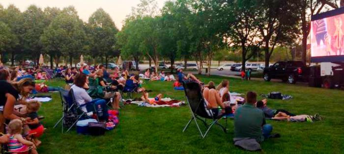 Group of employees outside watching a movie on a big screen